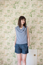 Young woman waering knitted sweater in front of printed wallpaper