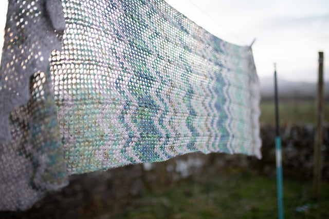 white knitted shawl hanging on clothesline