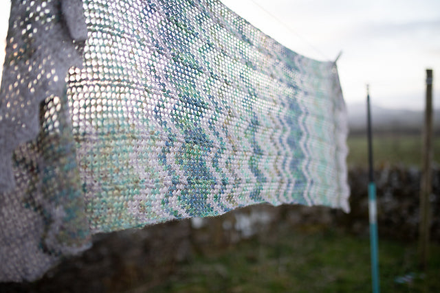 white knitted shawl hanging on clothesline