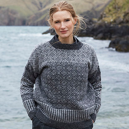 Woman wearing knitted sweater in front of a fjord