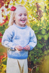 Little girl laughing wearing bue knitted sweater