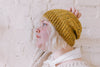 Young woman wearing gold-coloured knitted beanie cap