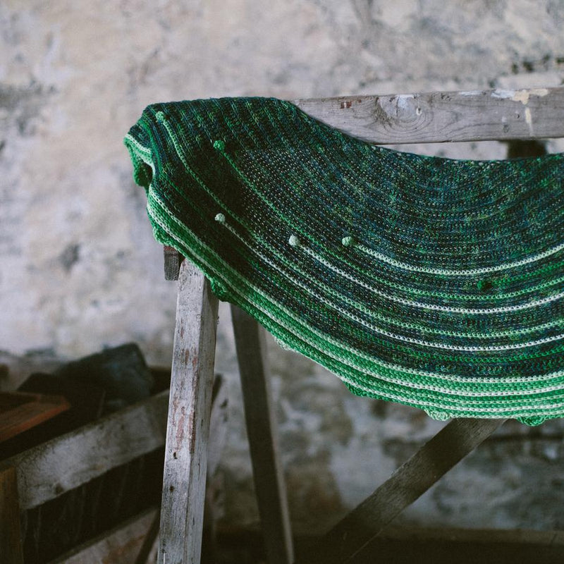 Green knitted shawl hanging on woode horse