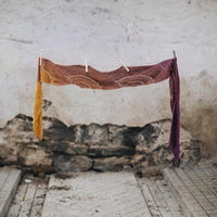 Burgundy coloured knitted shawl hanging on clothesline