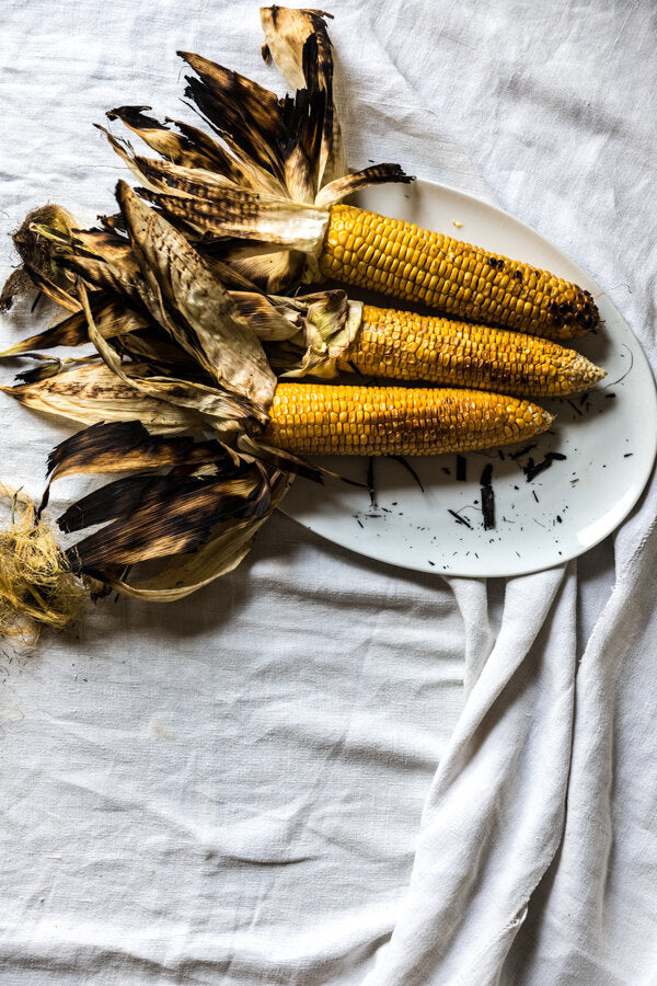 Barbecued corn cobs on a plate.