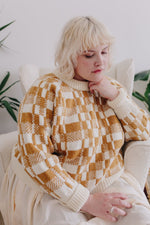 Woman pensive wearing gold-colored knitted sweater