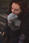 Young woman sitting on bench wearing knitted mittens