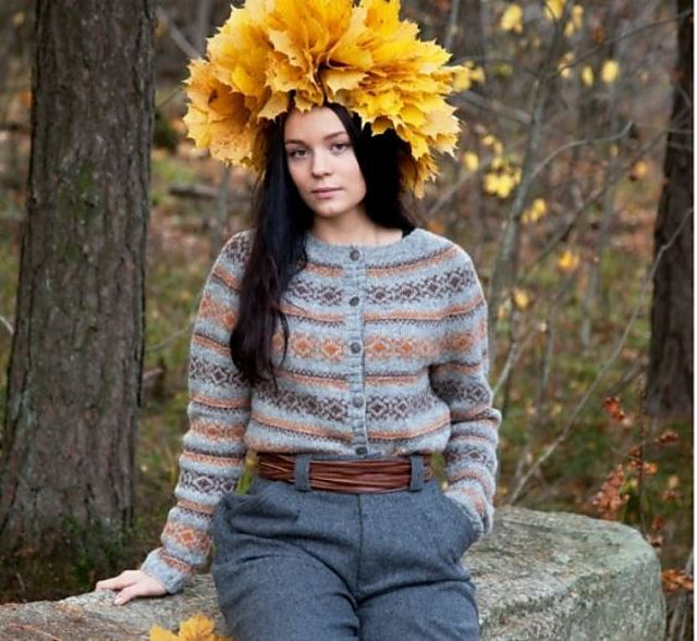 Young woman in forest wearing knitted blue sweater and large leaf laurel hat